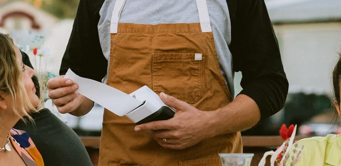 A server handing over a printed receipt.